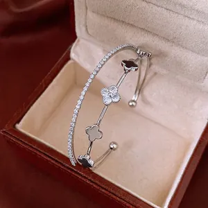 Silver double-layered open bangle with zircon-studded four-leaf clover design on beige velvet