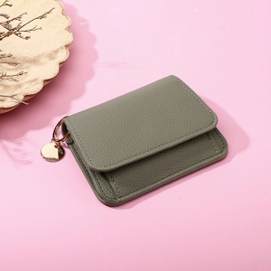 Detail of green litchi grain leather wallet with metal ring and round charm pendant