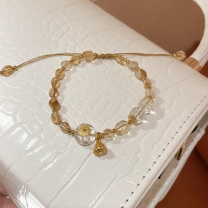 Close-up of adjustable crystal bracelet with lotus seed pod charm on leather texture