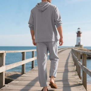 Rear view of grey linen hooded shirt and pants set on a scenic seaside boardwalk