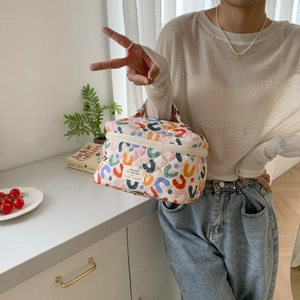 Detail of floral quilted cotton makeup bag with handle and aesthetic text label