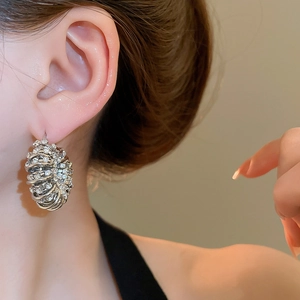 Close-up of a silver U-shaped earring with pavé rhinestones on a female ear model