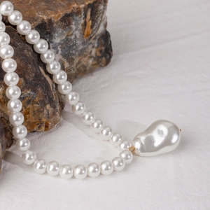 Dettaglio della collana con pendente in perla barocca appoggiata su pietra naturale