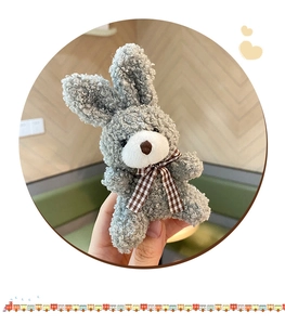 Close-up of grey plush bunny with brown checkered bowtie and soft curly fur texture