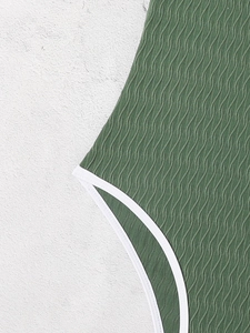 Close-up of olive green ripple textured fabric with white elastic trim on swimwear