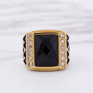Nahaufnahme eines Herrenrings in Gold mit großem schwarzen Stein und weißen Zirkonia-Steinen