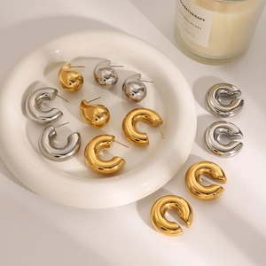 Macro detail of gold and silver waterdrop earrings on white ceramic dish with warm lighting