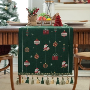 Detailed view of forest green Christmas table runner with festive jacquard pattern and tassels