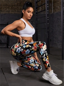 Women's floral yoga pants and white sports bra in a modern industrial gym setting