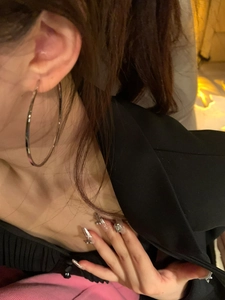 Close-up of model wearing large minimalist silver hoop earrings with black blazer