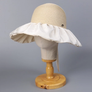 Détail d'un chapeau de soleil à large bord avec calotte en paille et bord plissé à boucle