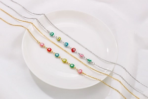 Detail of colorful Evil Eye beads on gold and silver layered necklaces over a white plate
