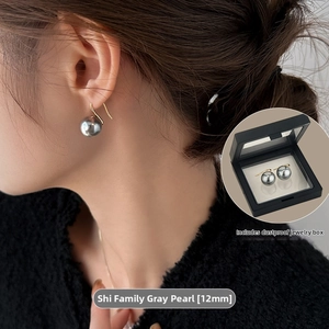 Close-up of 12mm grey pearl drop earrings on model with a gold hook and jewelry box