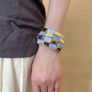 Detail of wide retro bracelet with blue marble patterns and gold metal geometric tiles