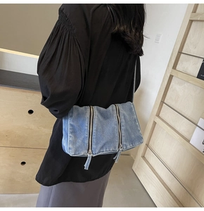 Détail du grand sac cabas en jean bleu avec double fermeture éclair porté en bandoulière
