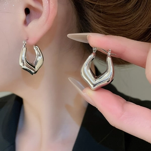 Detail of silver geometric V-shaped heart earrings with high-polish mirror finish