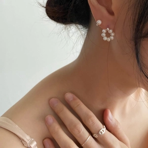 Detail of freshwater pearl hoop earrings and silver chain ring on model side profile
