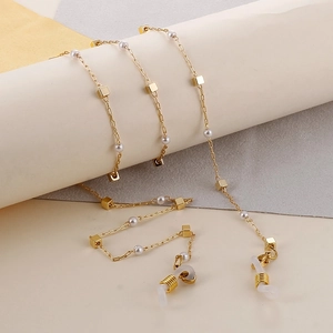 Detailed shot of golden eyewear chain featuring square metal blocks and faux pearls
