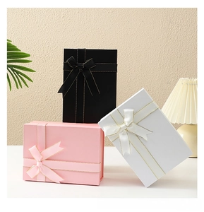 Detailed view of luxury foldable gift boxes in black, pink, and white with gold-edged ribbons