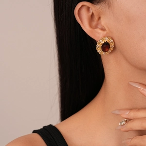 Close-up of vintage flower earrings with dark red gemstone and gold metal detail
