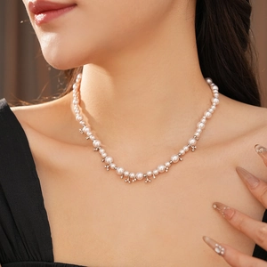 Close-up of elegant pearl necklace with zircon pendant on woman neck and collarbone