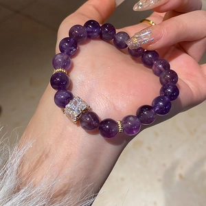 Detail of beaded bracelet with purple crystals and square faux diamond in gold setting