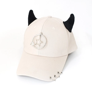 Detail of cream baseball cap featuring black horns, star pendant and metal brim rings