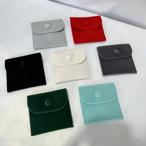 Flat lay of velvet jewelry pouches with snap buttons in seven assorted colors on white background