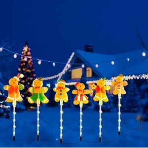 Solar Christmas gingerbread man stake lights with LED poles in a snowy night garden