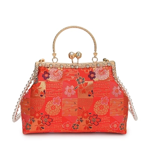 Detailed view of red silk embroidery with floral patterns and pearl golden clasp