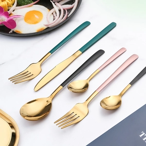 Set posate elegante in acciaio inox con manici colorati e teste dorate su marmo