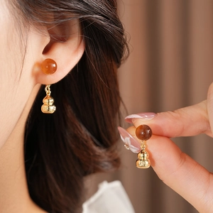 Detailed view of gourd-shaped drop earrings with brown beads and golden metal finish