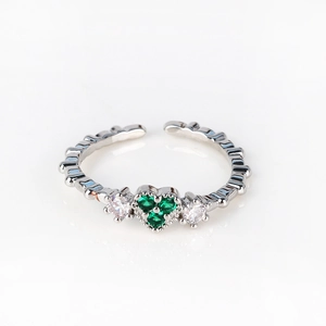 Macro detail of silver adjustable ring with three green heart-shaped cubic zirconia stones