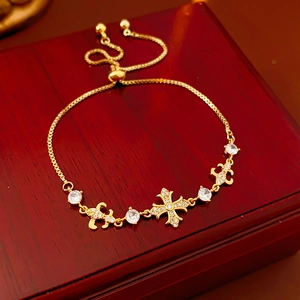 Détail d'un bracelet en or avec une croix en zircon blanc et un charme de fleur d'iris