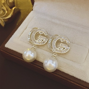 Detailed macro of gold-plated earring with sparkling crystals and a large pearl