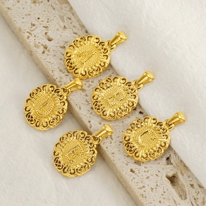 Gold round initial flower pendants on textured stone and white linen background