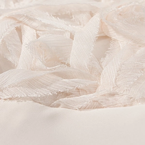 Macro shot of off-white fabric detailing refined tassel and frayed edge craftsmanship