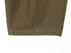 Detail of olive green cargo pants showing double-stitched hem and durable canvas fabric