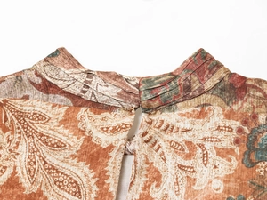 Gros plan sur l'encolure à motif paisley et détails plissés d'une mini robe marron