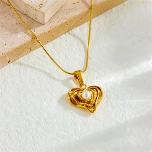 Minimalist gold heart pendant necklace with pearl on snake chain and stone background