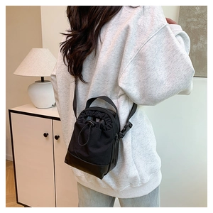 Mini black drawstring crossbody bag in canvas and leather styled in a cozy home setting