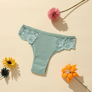 Gros plan d'une culotte en coton côtelé vert menthe avec dentelle sur fond chaleureux
