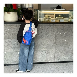 Détail du sac de poitrine bleu pour enfants en nylon avec numéro 21 rouge et lettrage