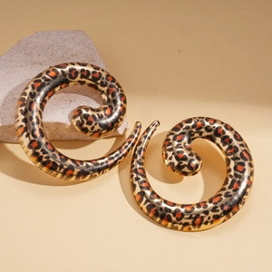 Detailed view of spiral leopard print earrings resting on a natural decorative stone