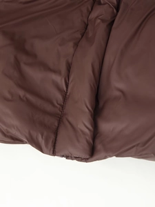 Gros plan sur le tissu lisse d'une doudoune marron foncé montrant les coutures