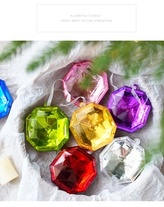 Colorful diamond-shaped acrylic holiday ornaments set on textured white paper background