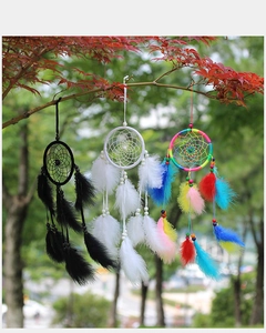 Three handmade dreamcatchers in black, white, and rainbow hanging on a tree branch