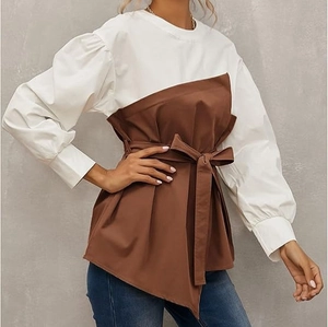 Detail of elegant patchwork shirt featuring white puff sleeves and brown belted waist tie