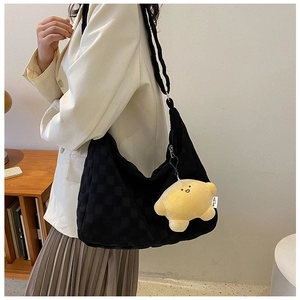 Detail of black checkered tote bag featuring a yellow plush star pendant and soft texture