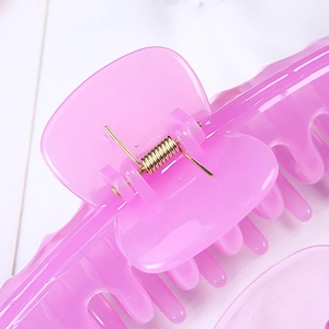 Detailed close-up of large pink plastic hair claw clip with focus on metal spring and teeth